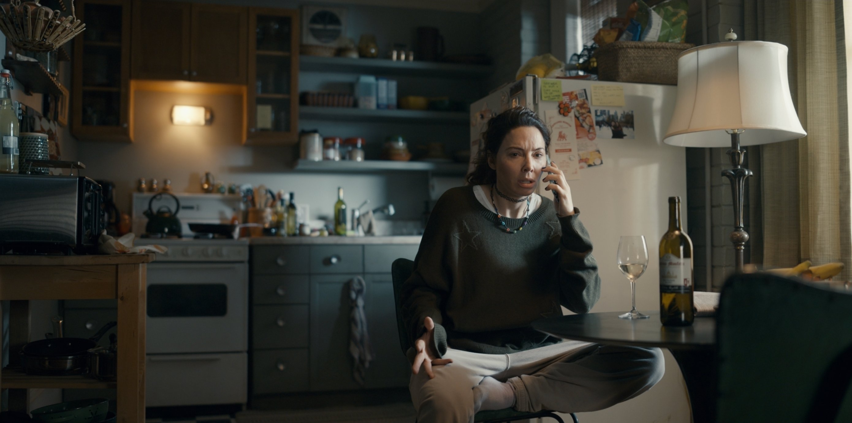 Brenda on the phone in her kitchen with custom set dressing graphics in Accused S1 E7