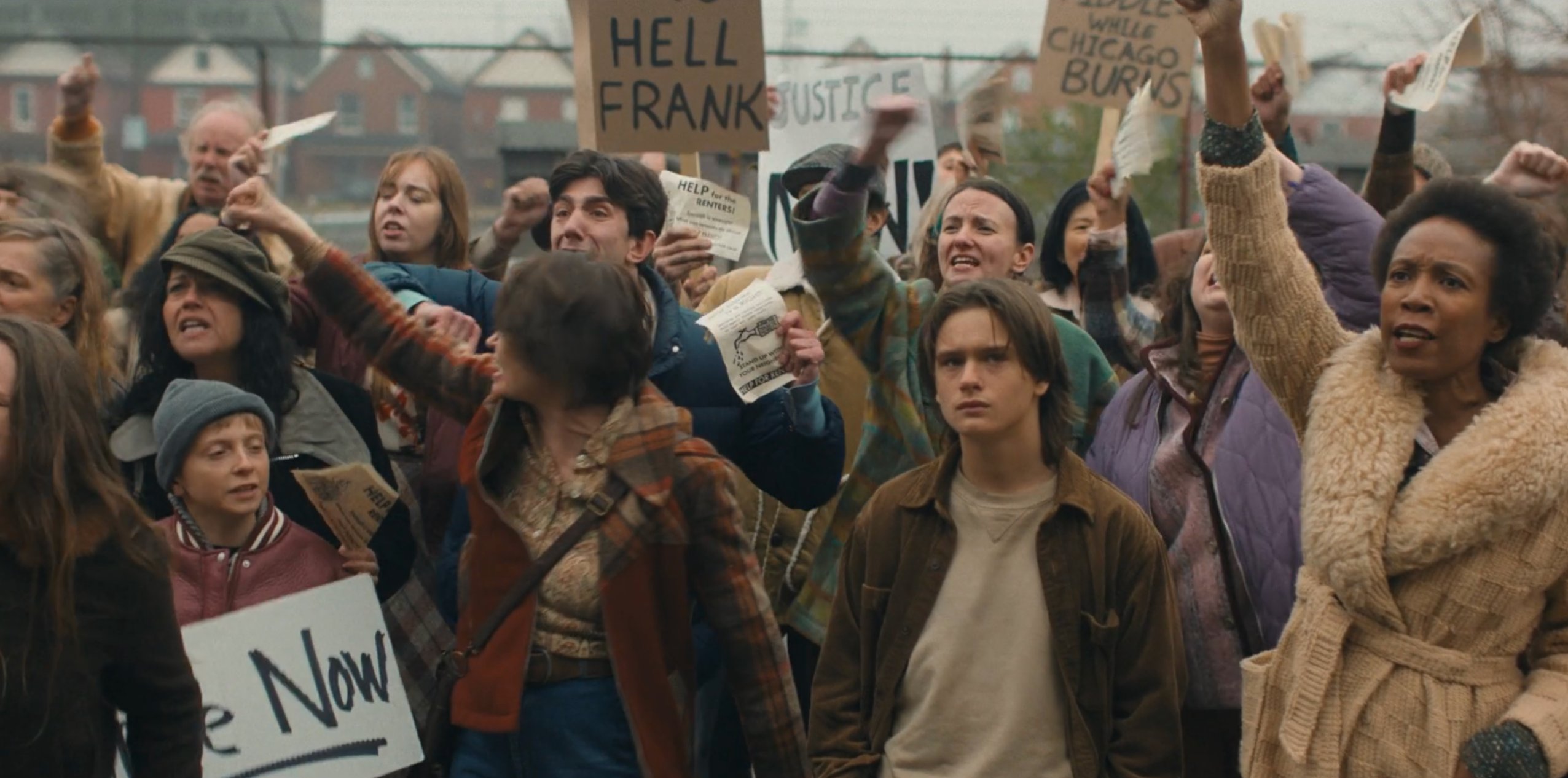 Crowd of protesters holding hand-lettered signs and pamphlets in Devil in Disguise E3