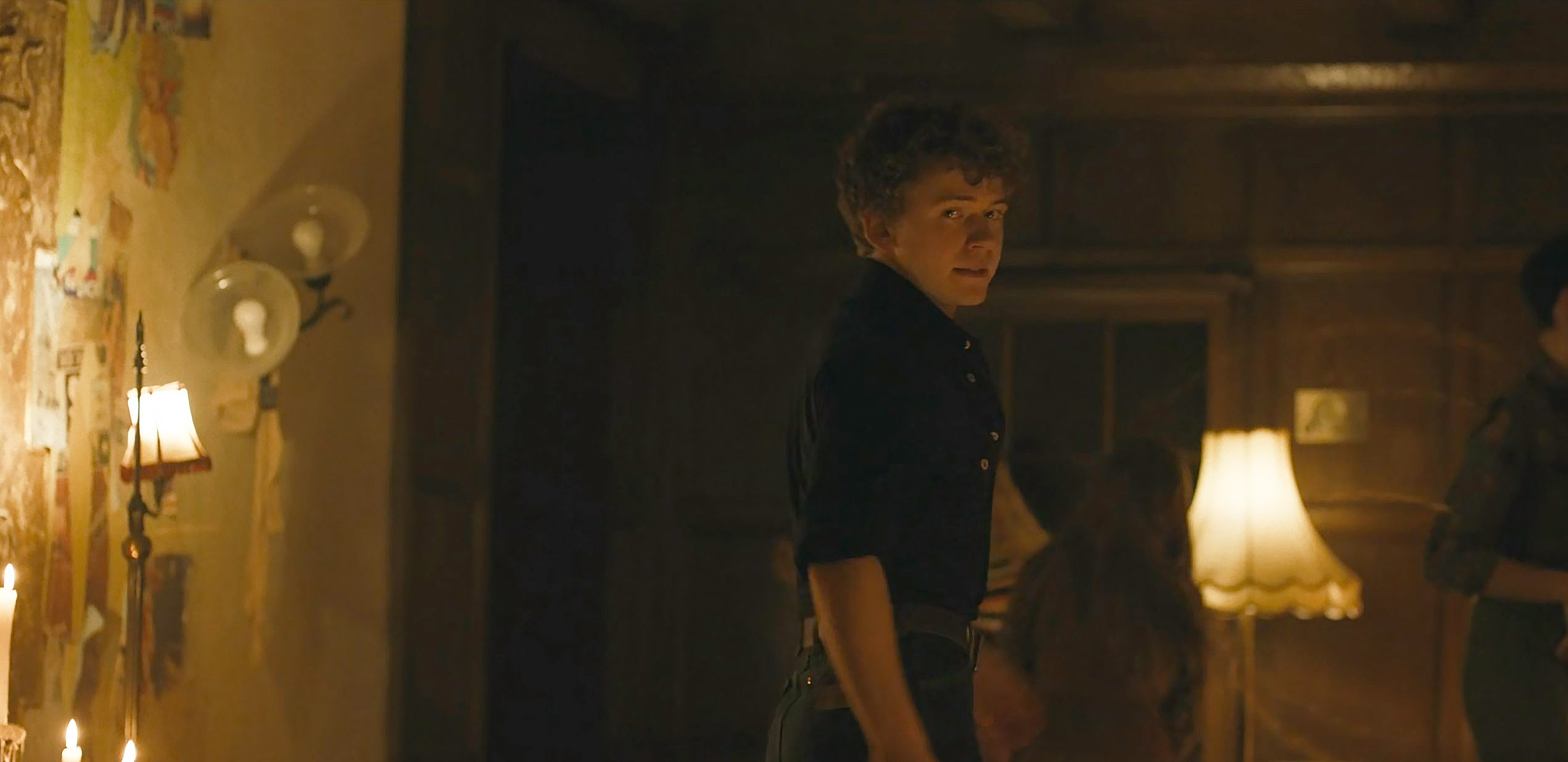 Character in a dimly lit room with custom collage wallpaper visible on the wall in Devil in Disguise E5
