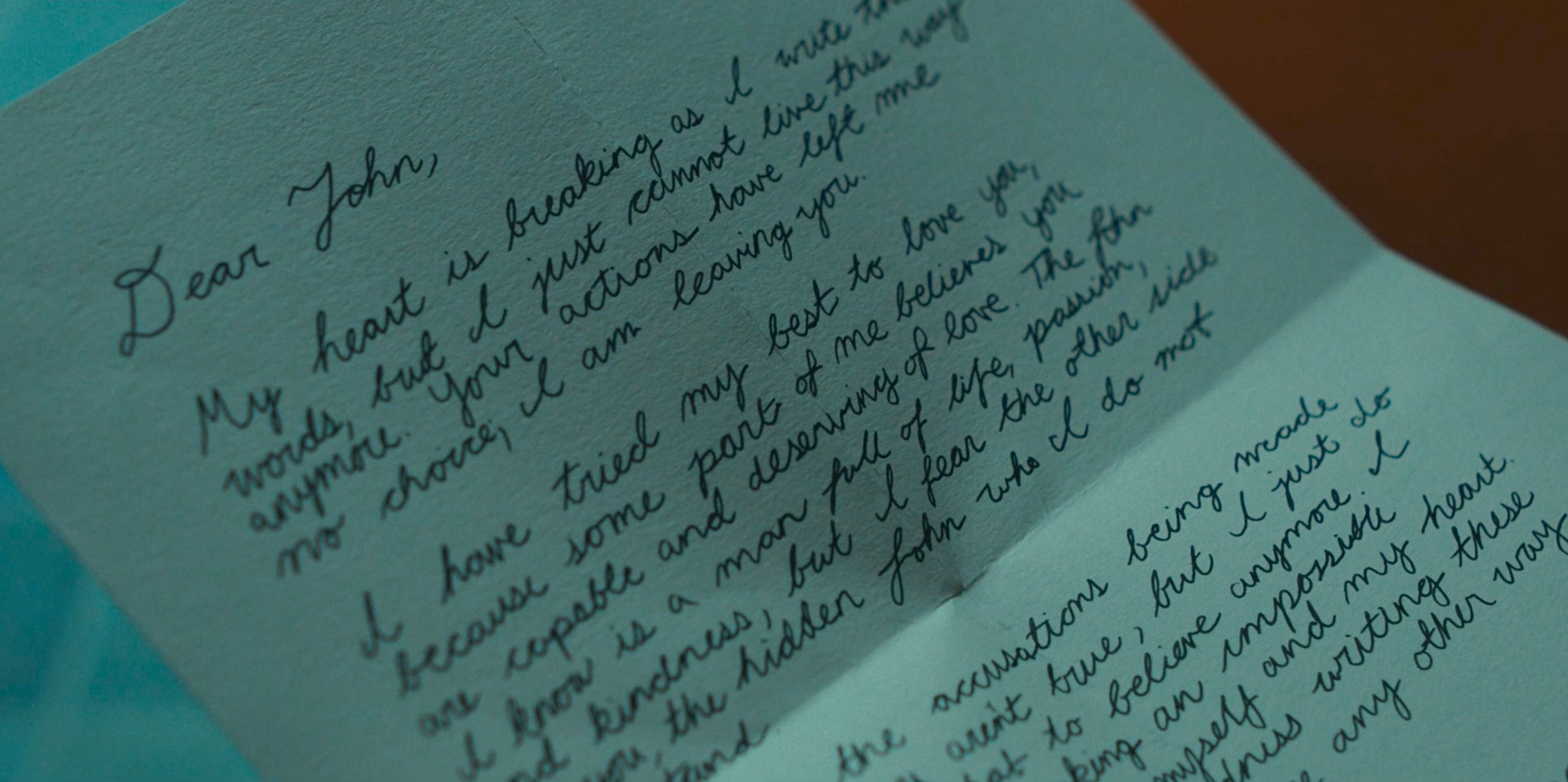 Hand-written letter beginning Dear John in cursive on folded paper in Devil in Disguise E6