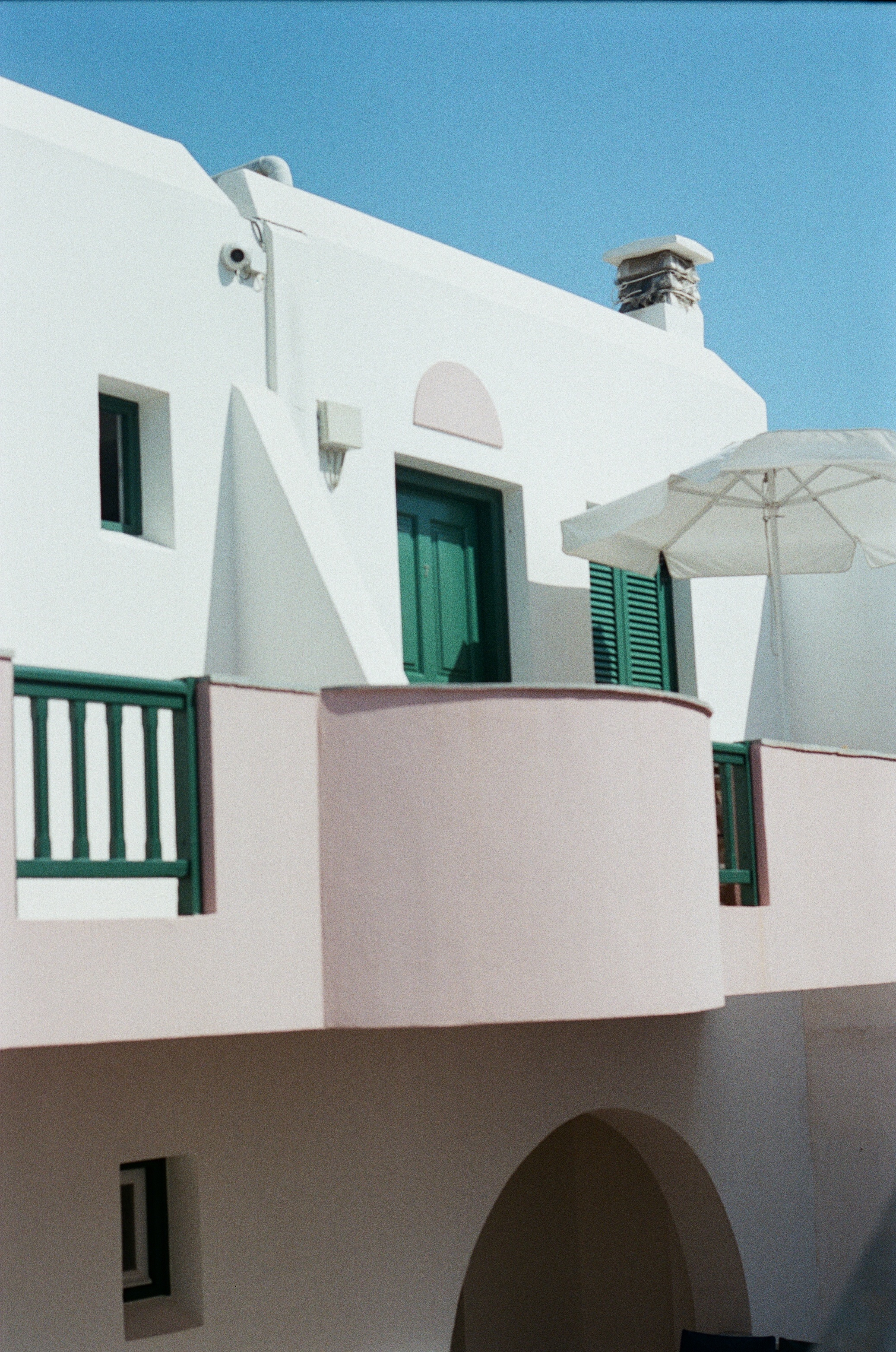 Cycladic house with dusty pink walls and deep green shutters
