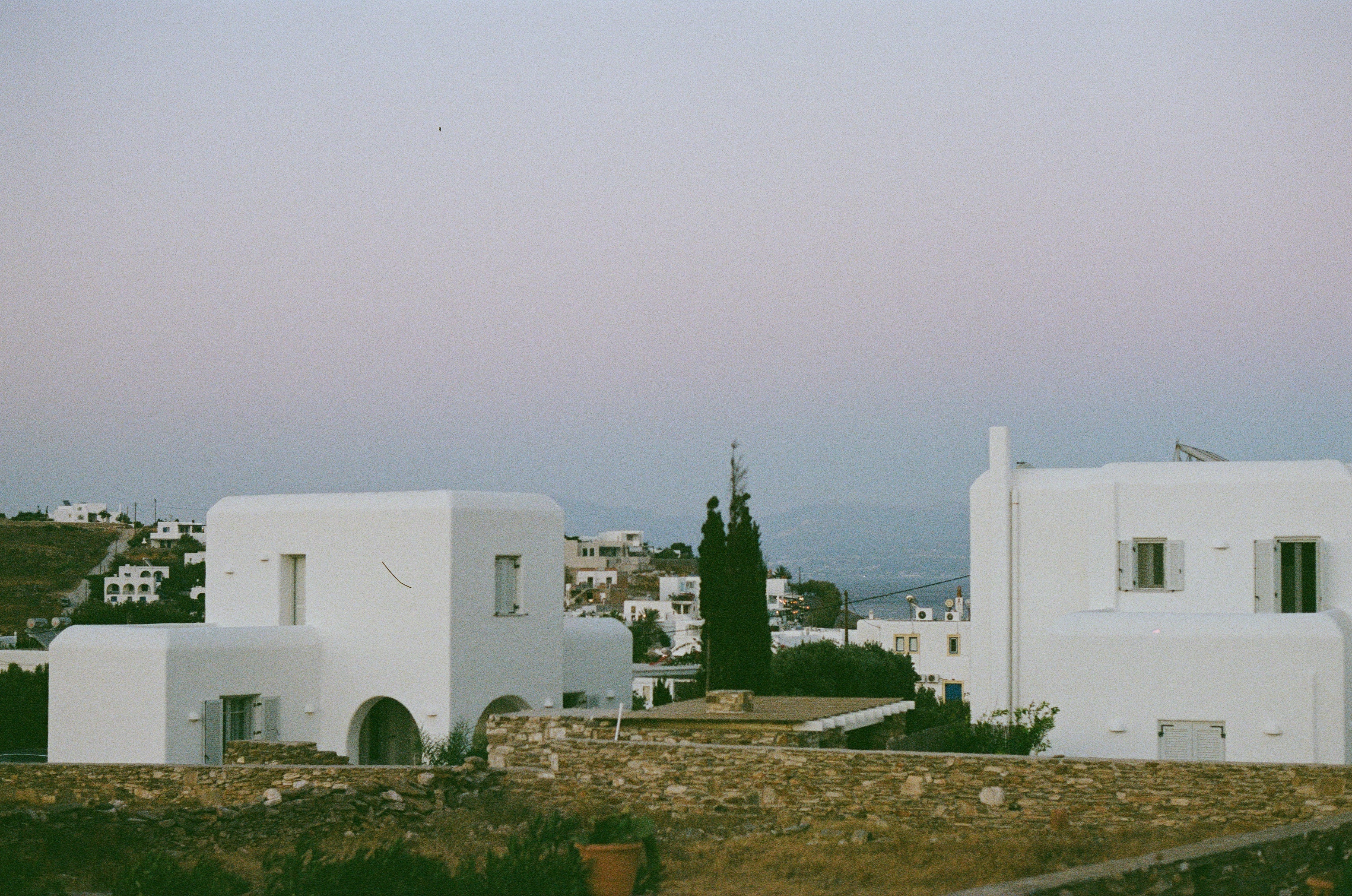 Greek hillside at dusk with white Cycladic houses under a lavender sky