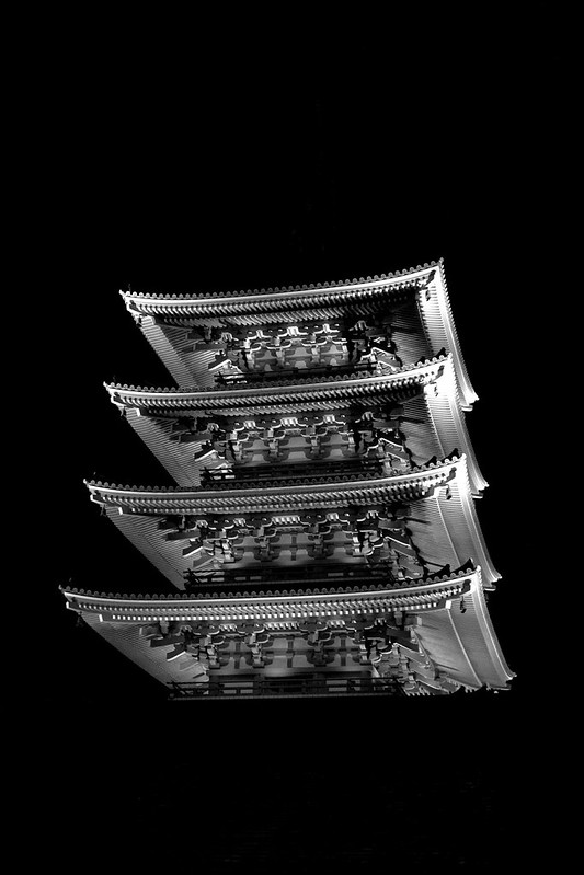 Stacked tiers of a Japanese pagoda lit at night against black