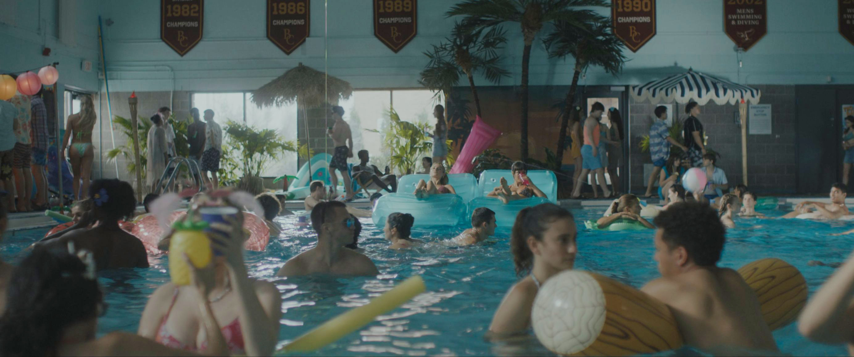 Indoor beach party with custom championship felt banners overhead in Tell Me Lies S3 E5